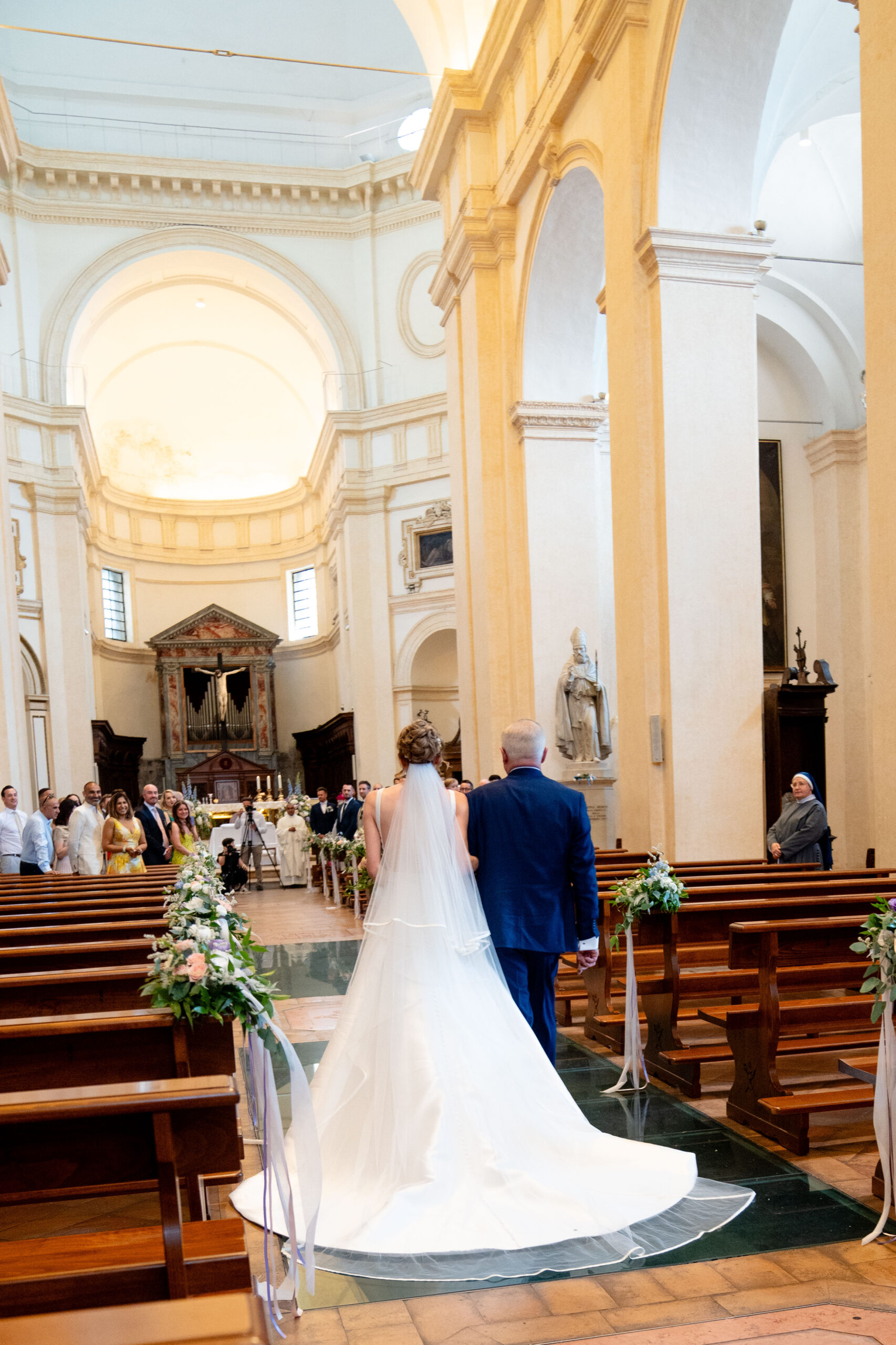 Bride and farther walking down the isle in Chapel of Assisi