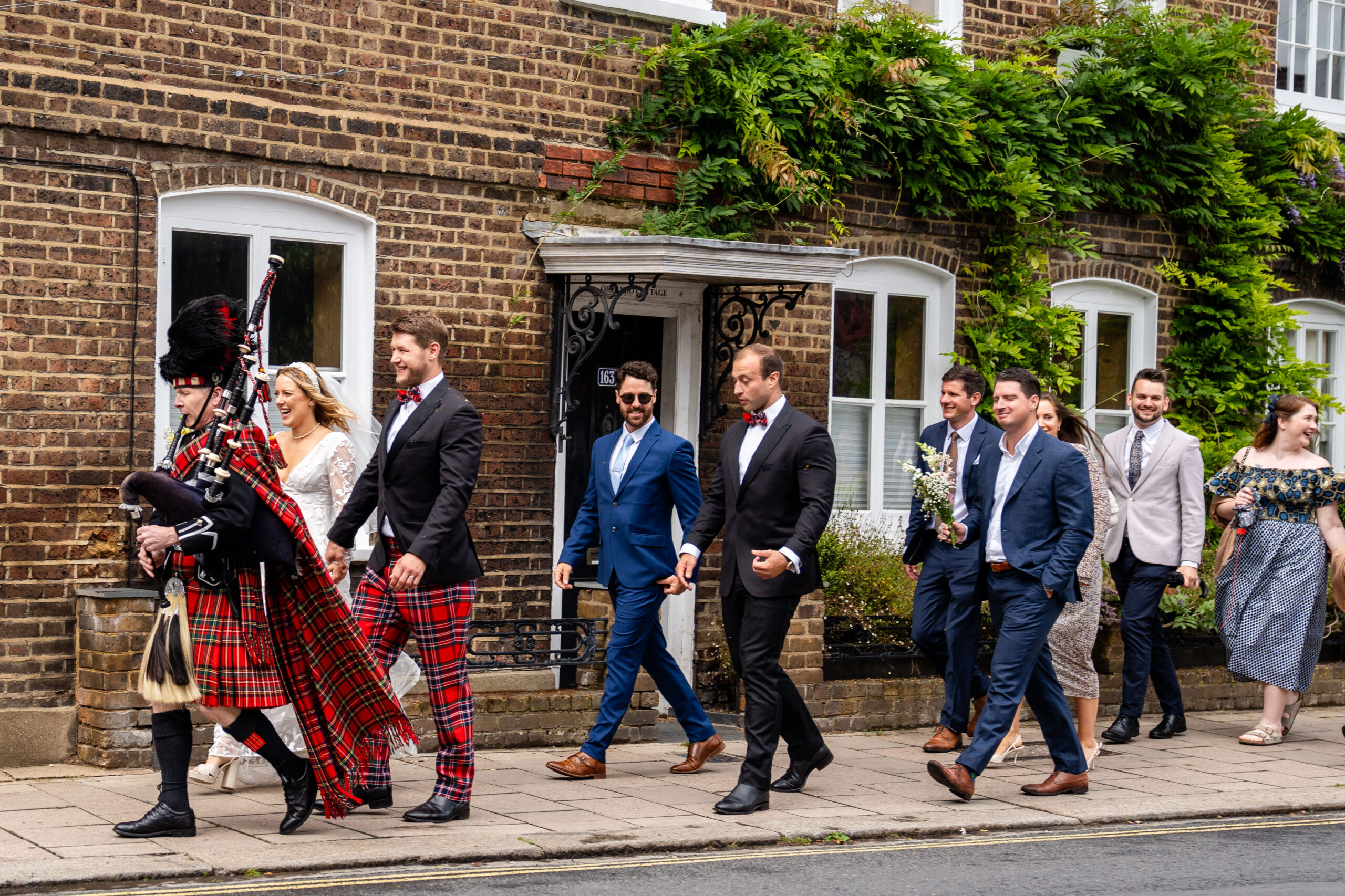 Richmond wedding photographer capturing wedding guests walking to the reception after ceremony with bagpiper