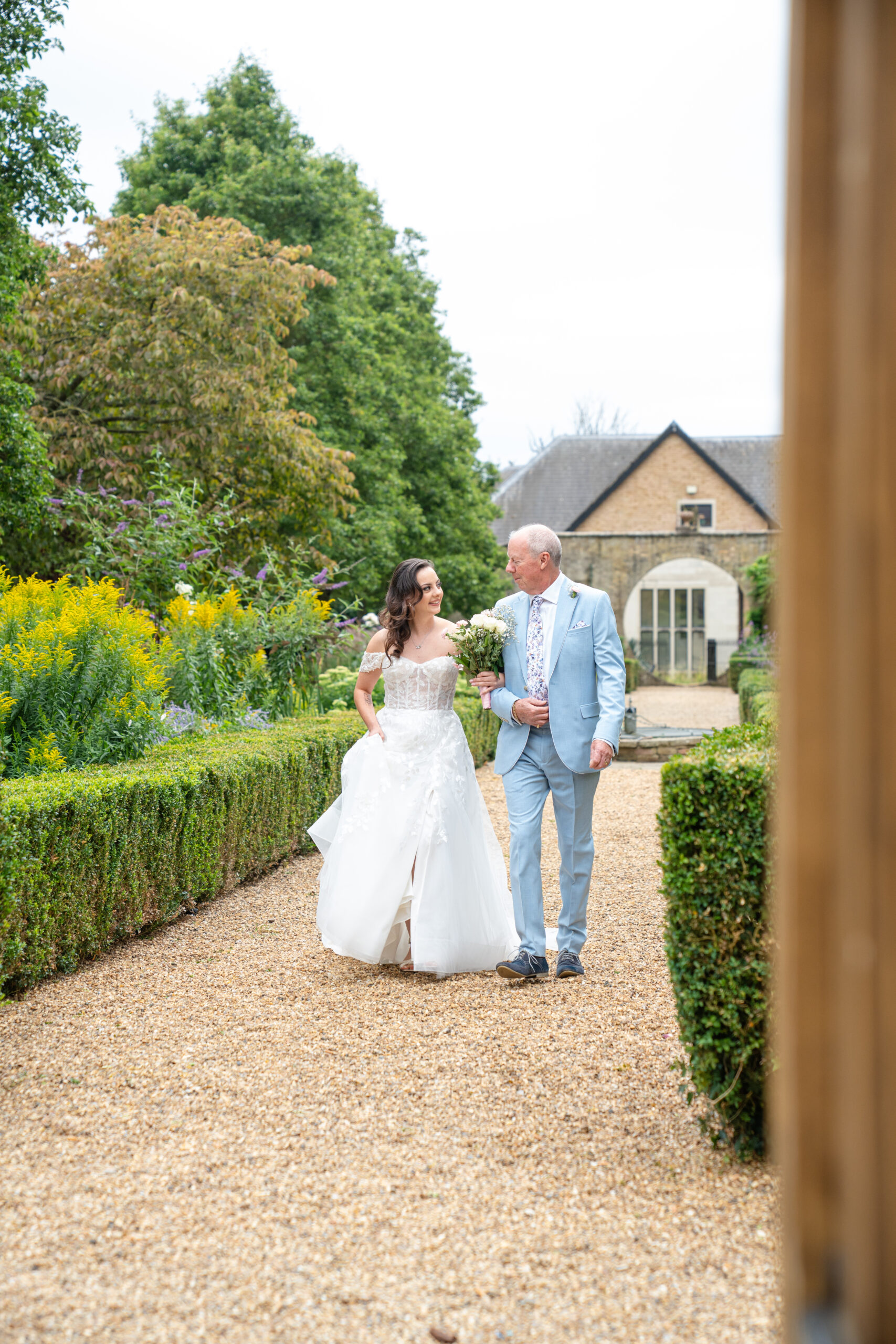 Father leading the bride to the ceremony at Hanbury Manor Garden Court 